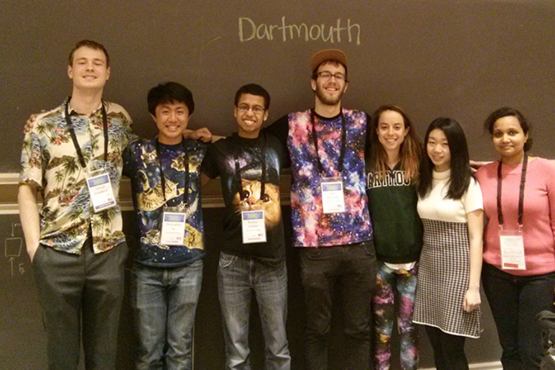 six students standing together in front of a blackboard with Dartmouth written on it in chalk