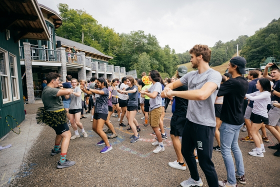 Students dance in the rain as part of first year trips