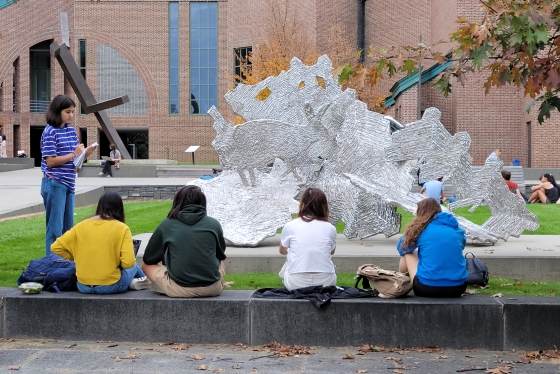 Five students studying a piece of sculpture on the Maffei Arts Plaza.
