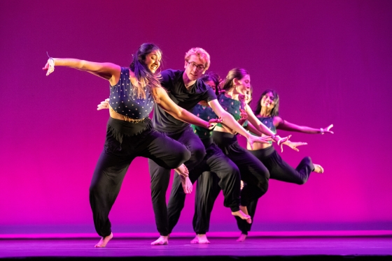 Members of dance troupe Raaz performing against a flaming pink background