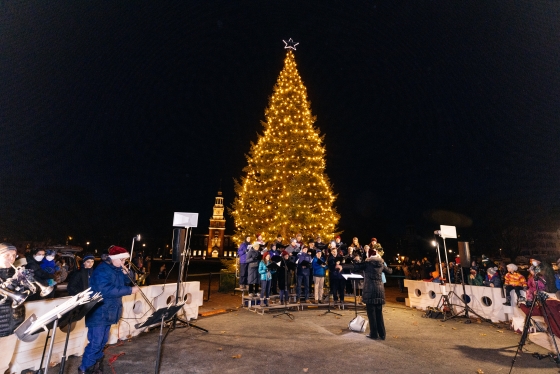 Lit Christmas tree with choir singing in front