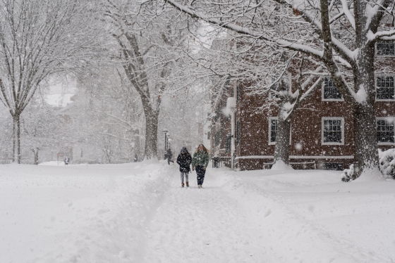 Two students walking past Baker in a snowstorm