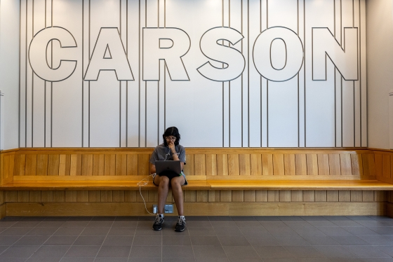 Ishika Jha studying on a bench under &quot;Carson&quot; sign
