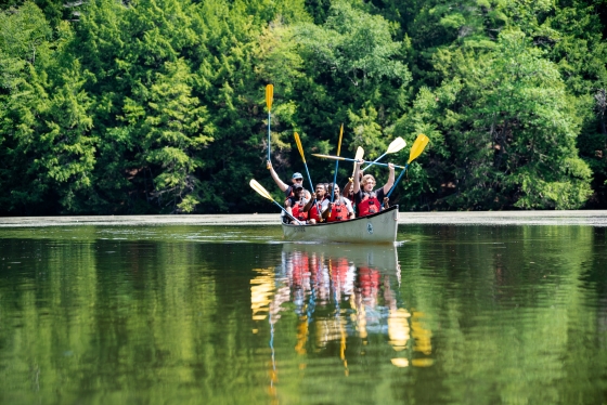 People in a canoe raising their paddles in the air