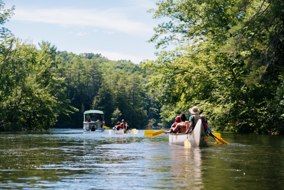 Two canoes following a pontoon boat on the Connecticut River