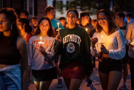 Students walking and smiling holding lit candles