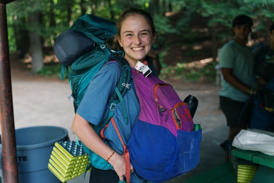 Student with multiple backpacks on, smiling