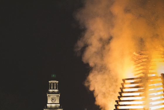 Green lights in Baker Tower glow while the bonfire burns.