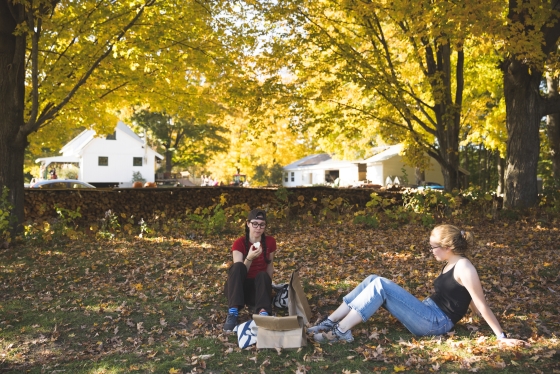 Two students sitting under the shade of yellow trees at Riverview farm
