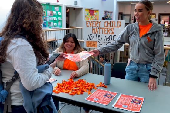 Native students hand out information about Orange Shirt Day.