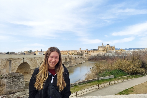Samantha Palermo in front of a historic Roman bridge in Spain