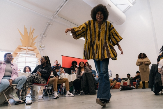 Student with an afro and yellow tunic walks down the the runway