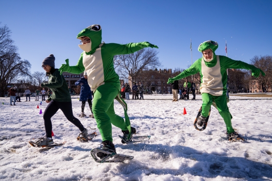 Students in green costumes racing in snowshoes