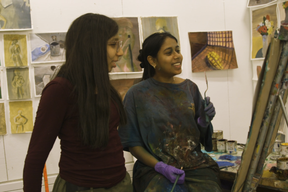 Two women smiling at a canvas in the art studio