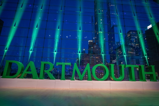 A 3D Dartmouth Wordmark lit up in front of a building
