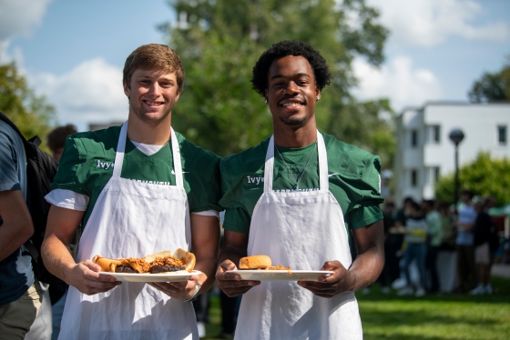 Football players serving food during the community cookout
