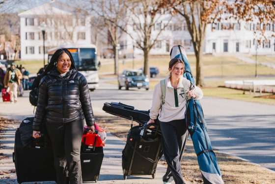 Student roll luggage across campus