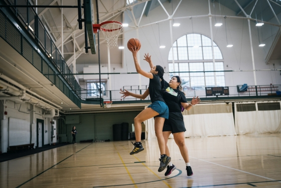 Two women play basketball