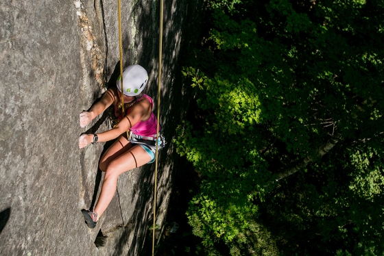 A student works her way up a rock wall on a climbing trip.