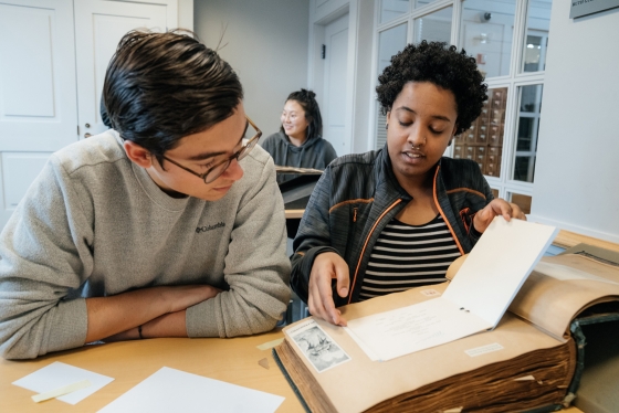 Two students look at a memory book in Rauner Library