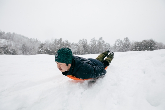 A student slides down a snowy hill