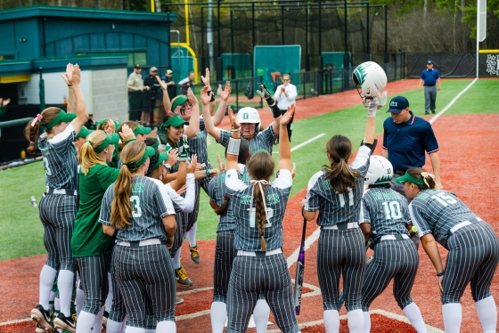 Softball player being greeted after scoring at home plate