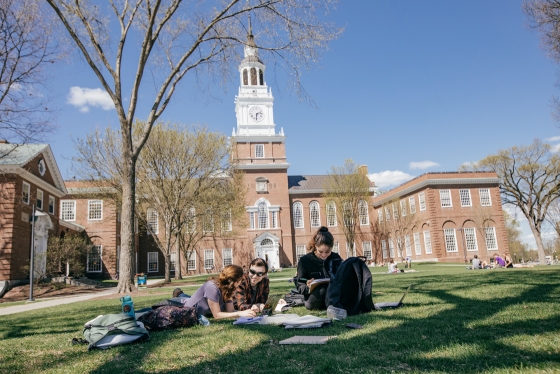 Students study on the lawn in front of Baker Library