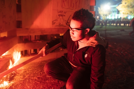Chase Alvarado-Anderson '23 crouches down to light the bonfire