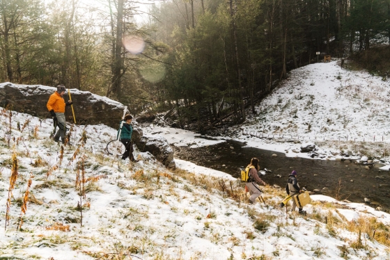 Four students walk down to a creek in Norwich to complete dam removal research