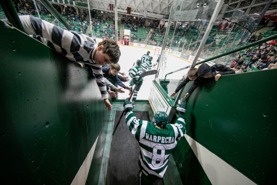 Dartmouth men's hockey player high-5s boys on his way to the ice.