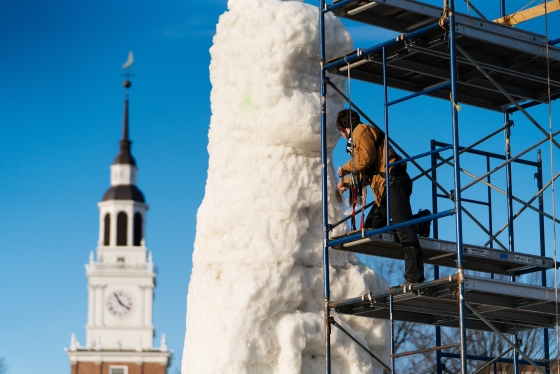 Dartmouth student works on large snow sculpture in front of Baker-Berry Library