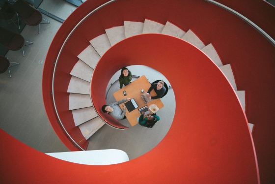 Overhead view, from within the red spiral stairway, of students studying.