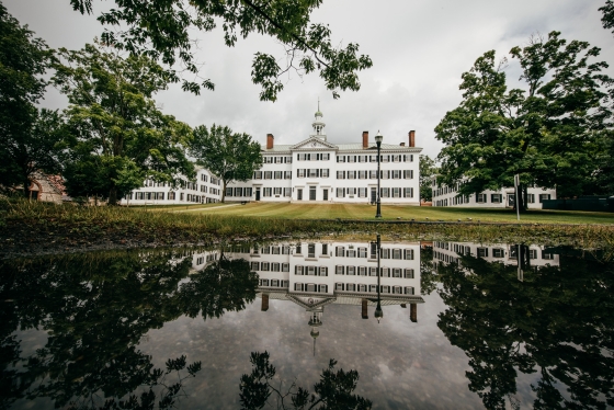 Dartmouth Hall is reflected in a puddle on a grey day.