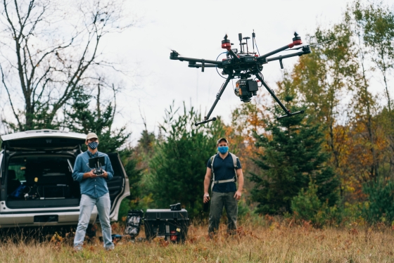 Two professors fly an autonomous drone system outside.