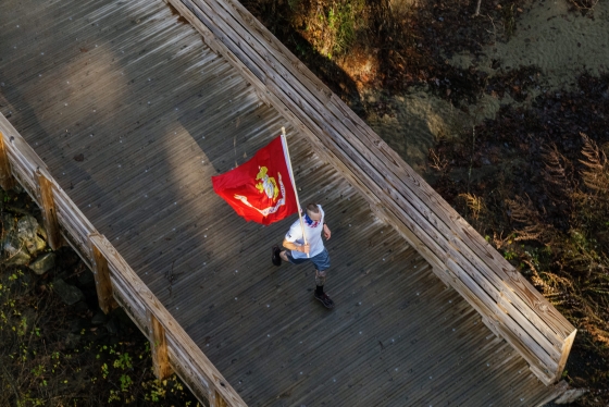 Jason Mosel running over a bridge on the Hanover Golf Course carrying the Marine Corps flag