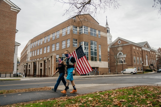 Jason Mosel carries the American flag past Carson Hall with his wife