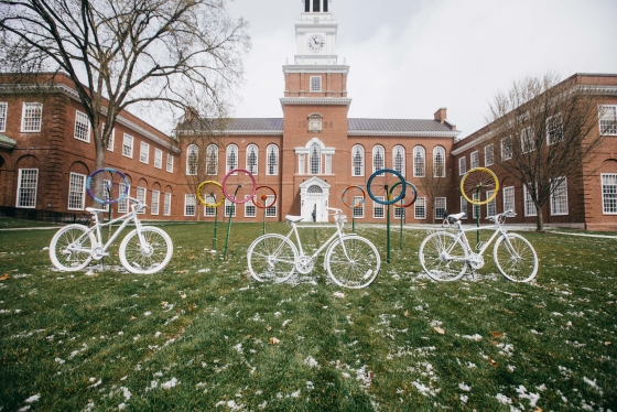 Three all white bicycles and colorful tire sculptures displayed on Baker Lawn