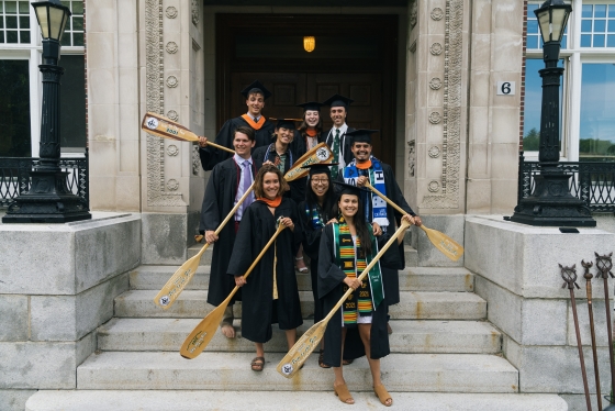 Graduates holding &quot;Trip to the Sea&quot; paddles in front of Robinson Hall.