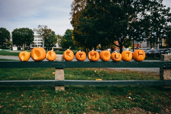 Pumpkins lined up on the senior fence on the Green with the word &quot;Dartmouth&quot; carved out one letter per pumpkin.