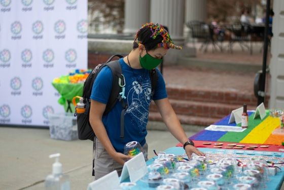 A student wearing a colorful unicorn hat chooses a Pride Week cupcake