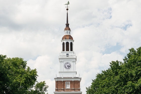 the top of Baker tower surrounded by green trees with white clouds in the background