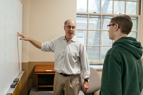 Phil Hanlon ’77 standing with a student at a white board