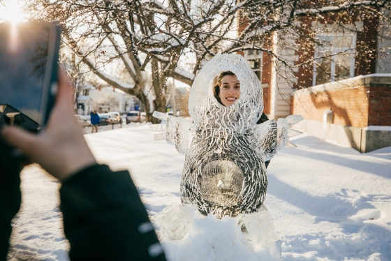 Dartmouth student gazes through hole in ice sculpture