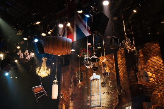 Stage shows chairs, barrel, chandeliers hanging from the ceiling