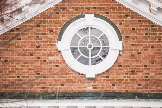 Round white window surrounded by brick
