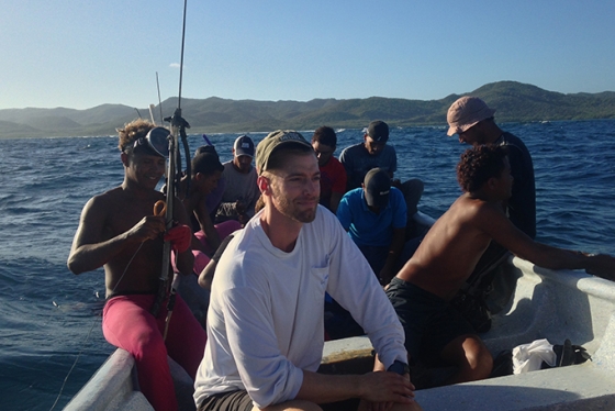Tyler Pavlowich sitting in a boat with a group of fishermen