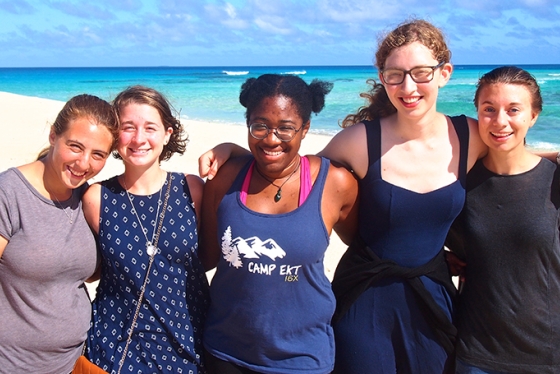 a group of female students standing together on a beach