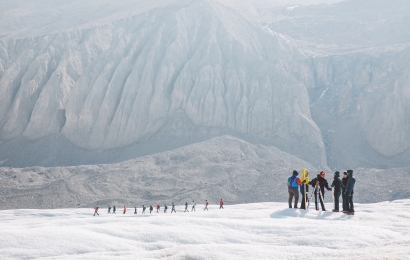 Students hiking on a glacier in single file.