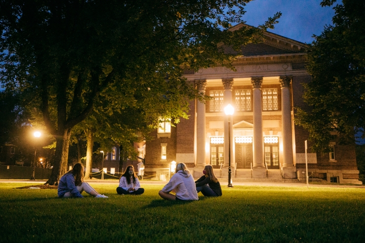 Students sit on the Dartmouth Green at night