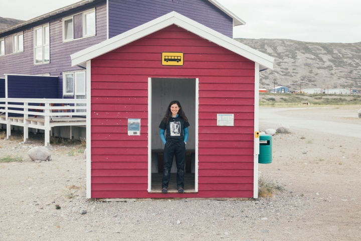JSEP student Ella Lubin stands in the doorway of a smlal red building in Kangerlussuaq.